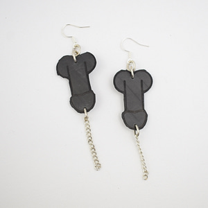 Recyled Jewellery: A pair of Penis Earrings shaped like bones, crafted from black material with a matte finish, each hanging from a silver chain and hook, against a plain white background. @ Reblack Shop