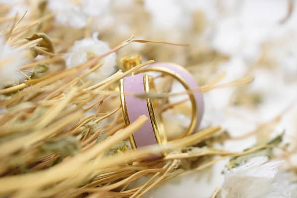 Recyled Jewellery: Close-up image of a dried floral arrangement with delicate textures, featuring pale pink accents and subtle green hues amongst golden beige dried grasses, accented with recycled jewellery. @ Reblack Shop