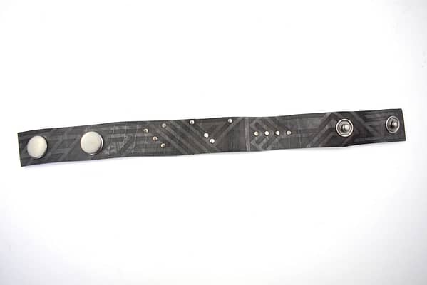 Recyled Jewellery: A Maori Tribal Bracelet with symmetrical snap fasteners and a pattern of white dots on a dark gray background, repurposed into eco-friendly jewelry, isolated on a white surface. @ Reblack Shop