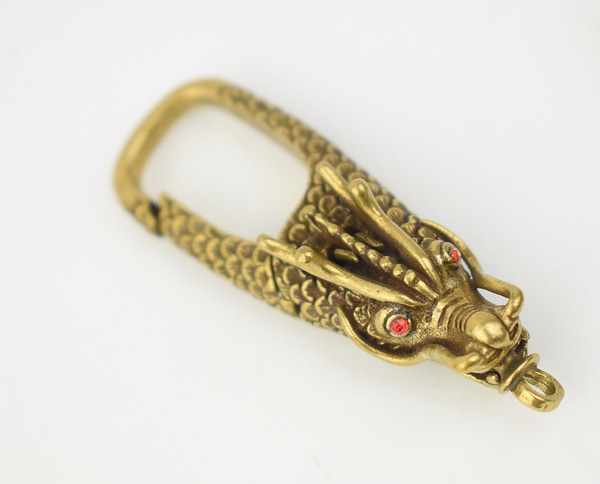 Recyled Jewellery: A close-up image of an eco-friendly Dragon Carabiner with red gem eyes, set against a plain white background. @ Reblack Shop