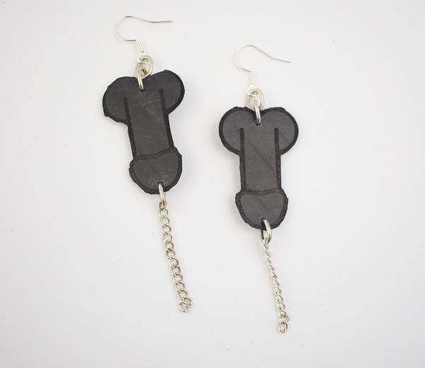 Recyled Jewellery: A pair of eco-friendly handmade Penis Earrings featuring black bone-shaped pendants with small chain links dangling from one of them, against a white background. @ Reblack Shop