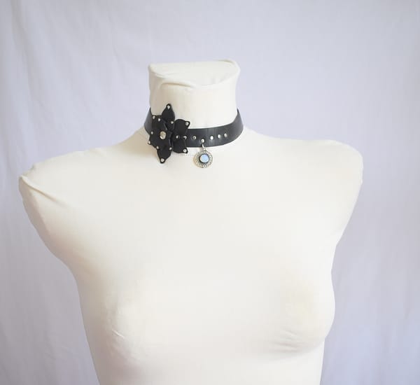 Recyled Jewellery: A mannequin displays a Flower XL Choker Moon Stone adorned with a decorative moon stone pendant and silver accents. The background is a plain white fabric. @ Reblack Shop