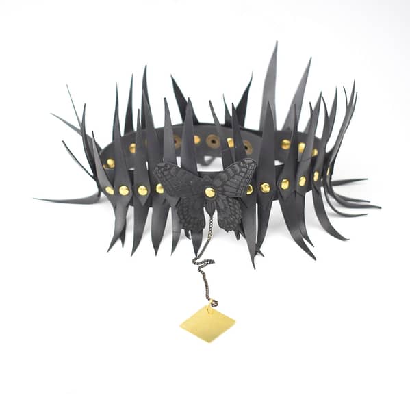 Recyled Jewellery: A BerlinWinter Butterfly Choker decorated with spikes and featuring a central black butterfly pendant, attached to a small dangling gold tag. This piece exemplifies eco-friendly jewelry, crafted with upcycled materials. @ Reblack Shop