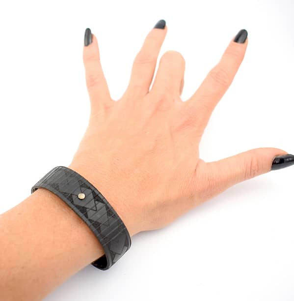 Recyled Jewellery: A woman's hand with black nail polish on a white background, wearing a stylish Maori Tribal Bracelet made from repurposing jewelry. @ Reblack Shop