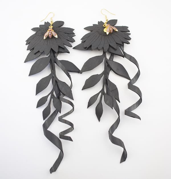 Recyled Jewellery: A pair of eco-friendly, black, leaf-shaped Pollinating Flowers earrings with long, flowing ribbons attached, against a white background. @ Reblack Shop