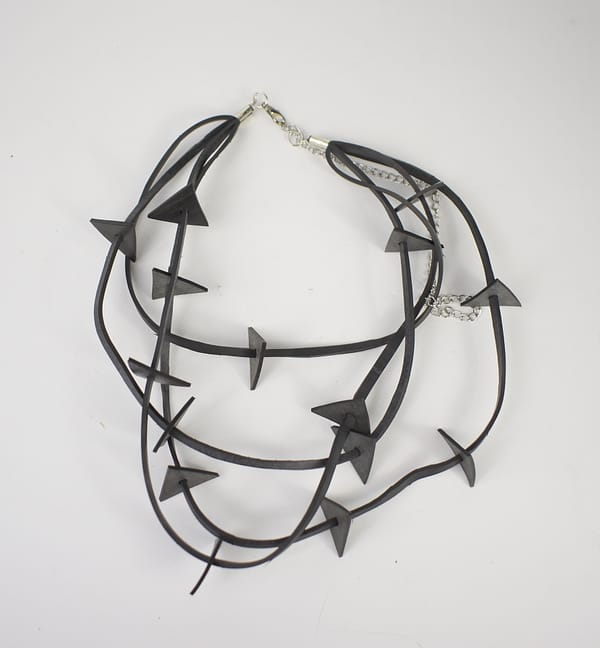 Recyled Jewellery: A multi-strand, eco-friendly Triangle on Wire Necklace featuring matte black arrows on a white background, with each strand connected by a silver clasp. @ Reblack Shop